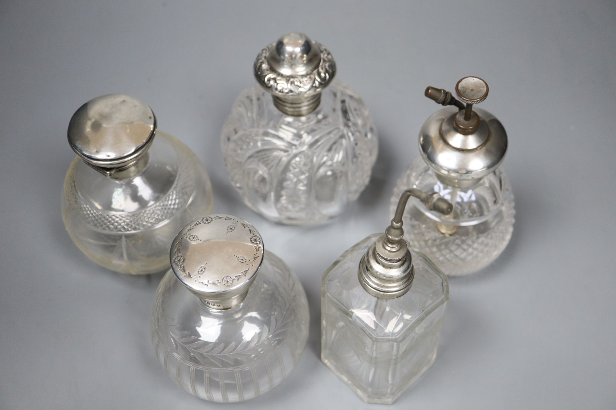 Two silver mounted glass atomisers and three silver mounted glass scent bottles, tallest overall 16cm.